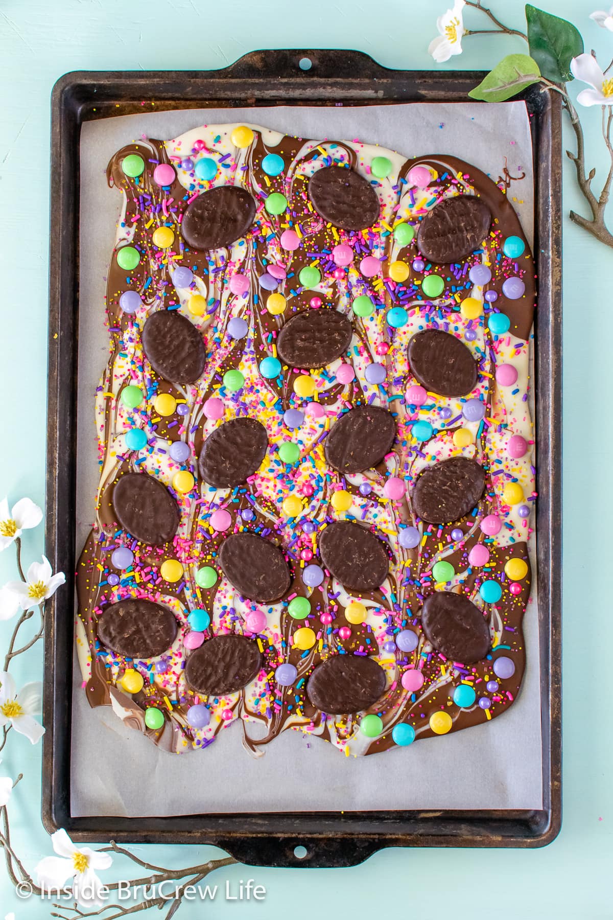 A pan of swirled chocolate bark topped with candies and sprinkles.