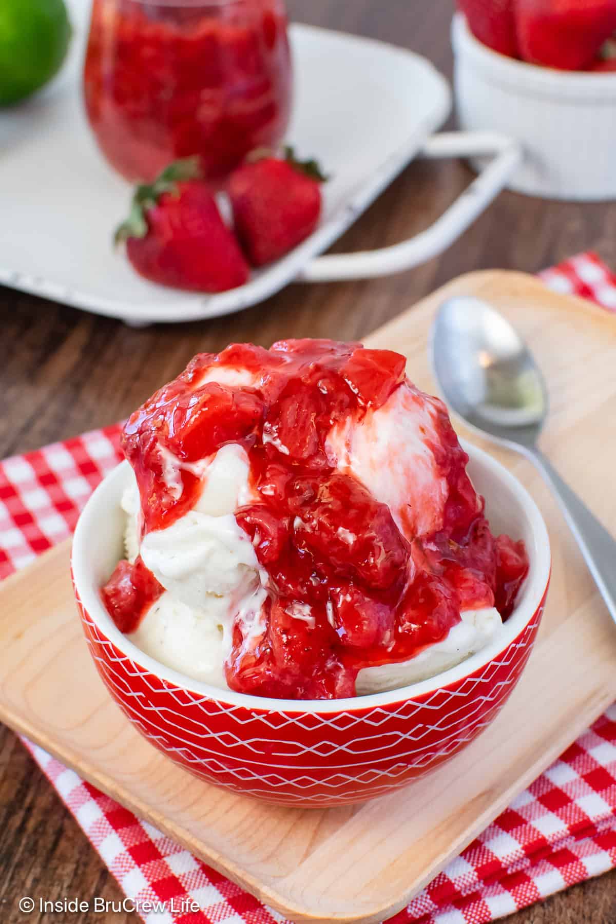 A bowl of vanilla ice cream topped with a honey strawberry sauce.
