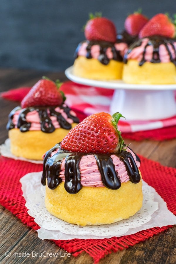 Two no bake strawberry mousse shortcakes on white doilies with a cake plate behind them.