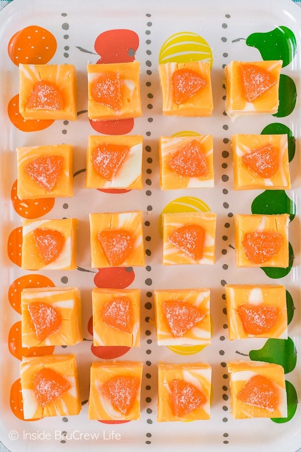 An overhead picture of a white tray with orange squares topped with an orange candy on it.