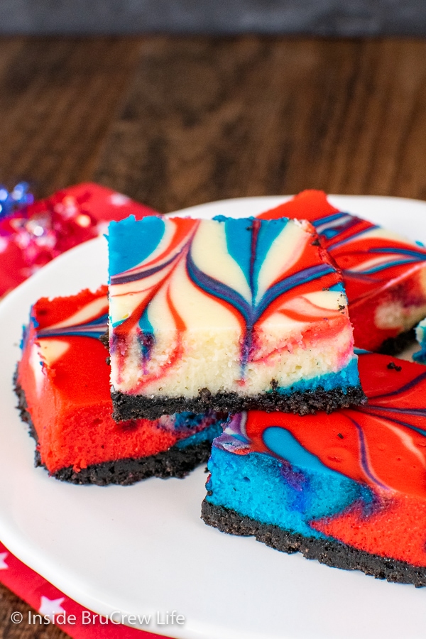 A white plate with a few red white and blue cheesecake bars stacked on it
