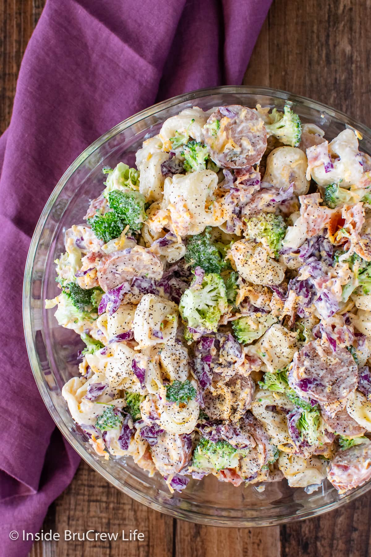 A large bowl filled with a creamy tortellini salad with broccoli.