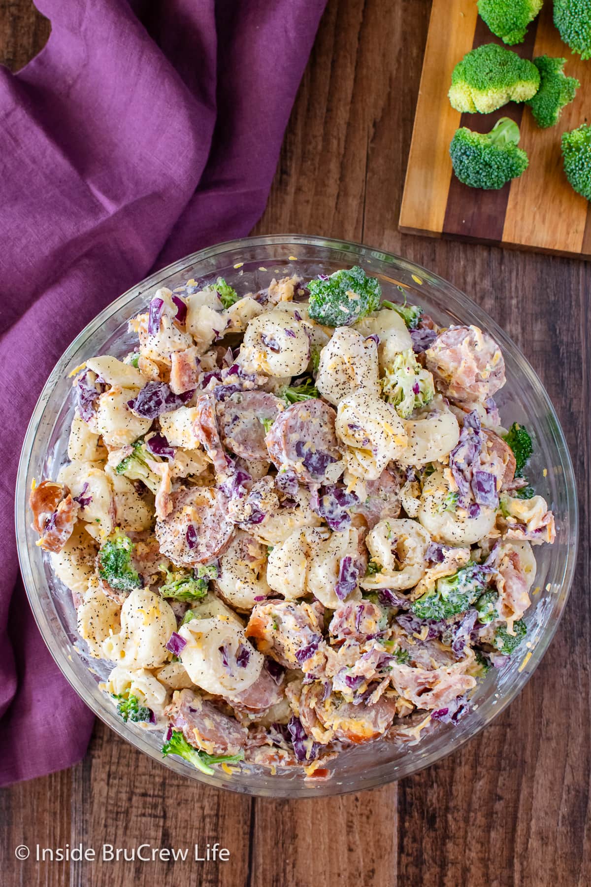 A large bowl filled with a creamy tortellini salad with broccoli.