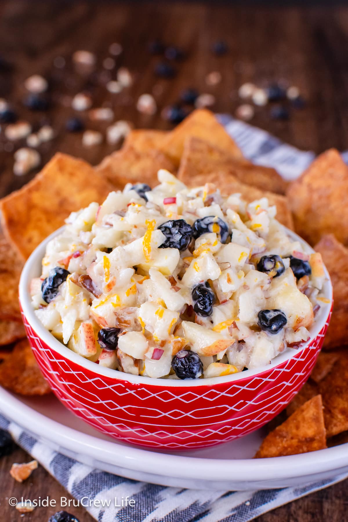 A red bowl filled with diced apples with an orange yogurt coating.