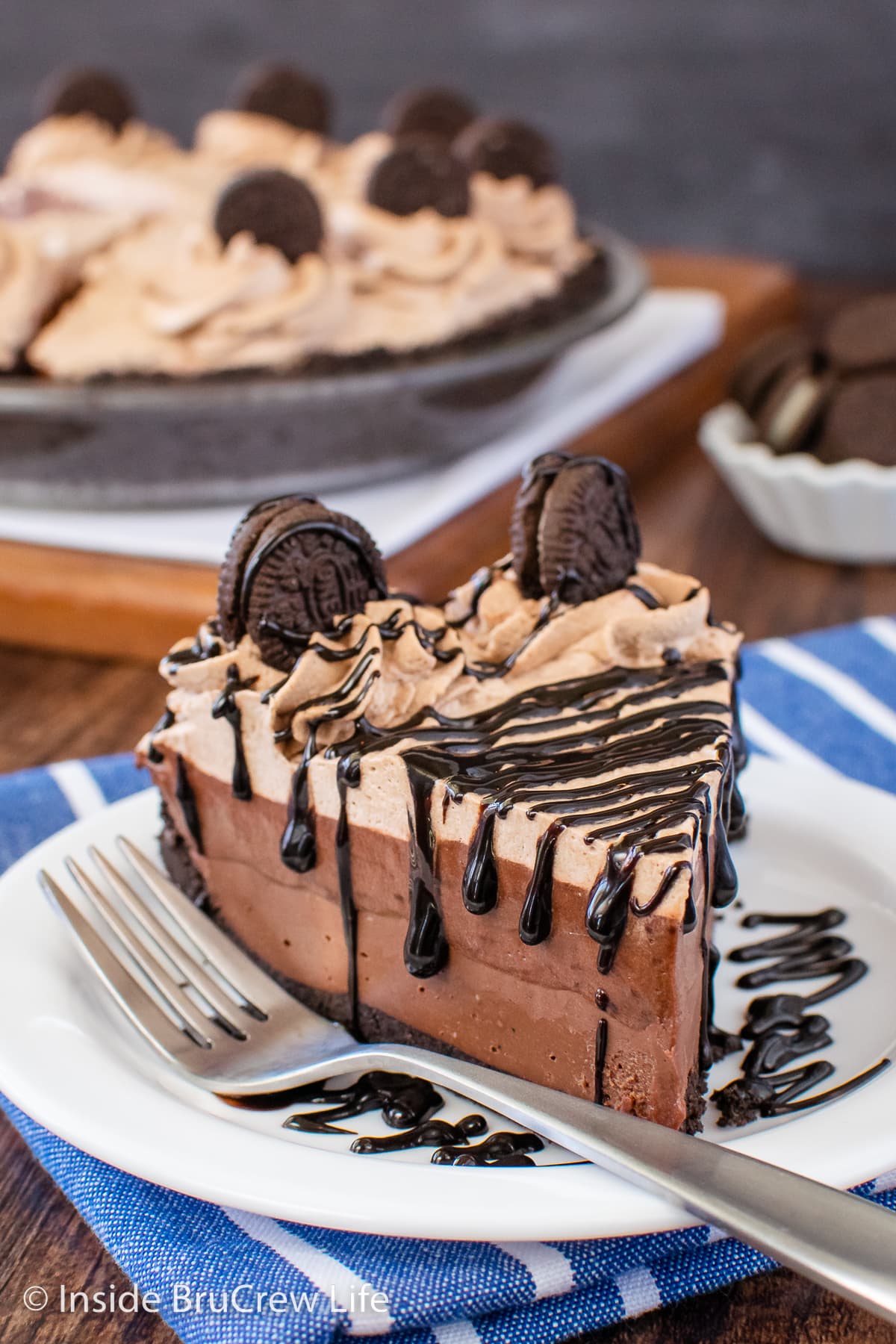 A slice of chocolate pie with hot fudge drizzles on a white plate.