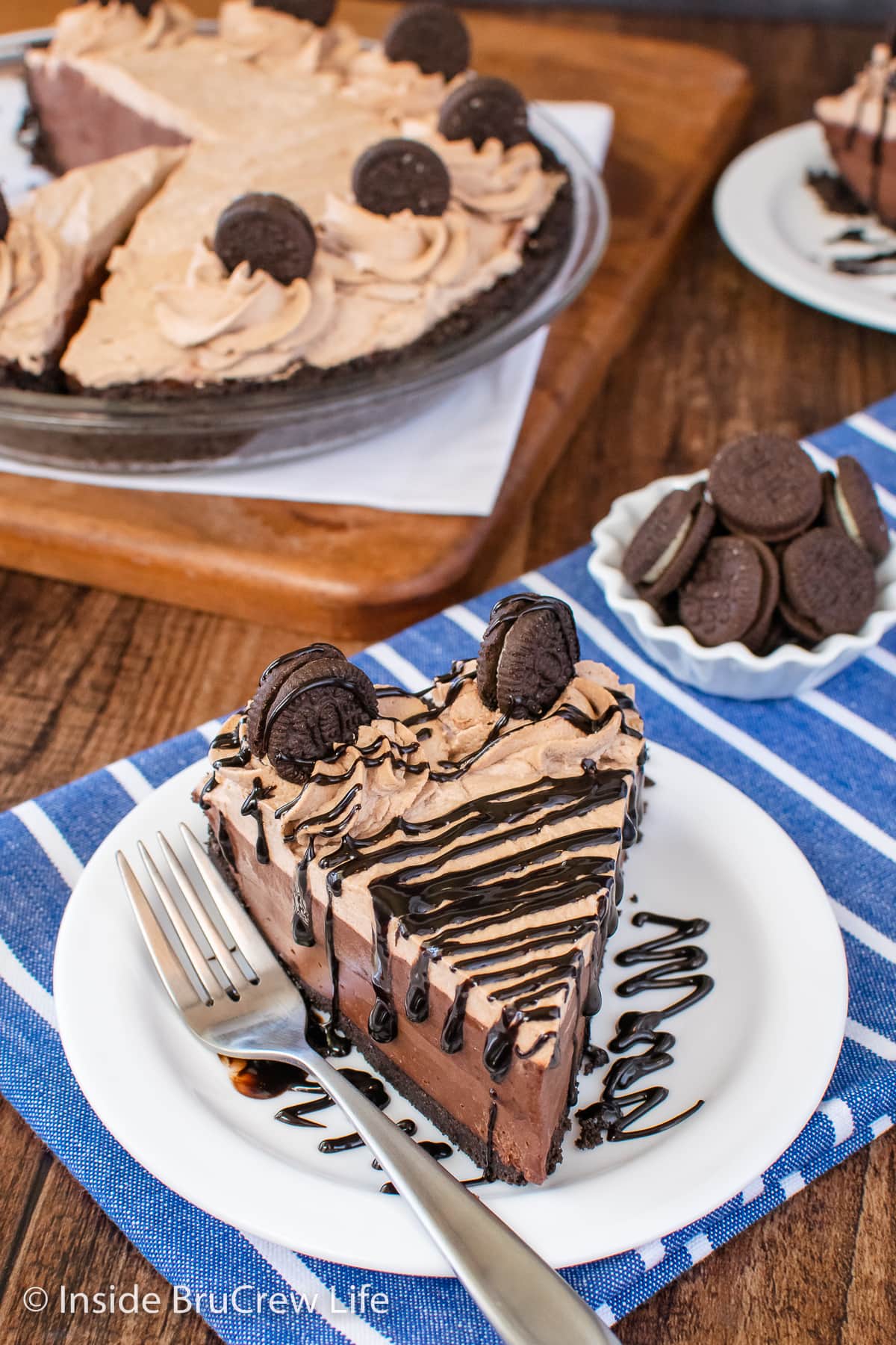 Chocolate pie slice topped with hot fudge and chocolate cookies.