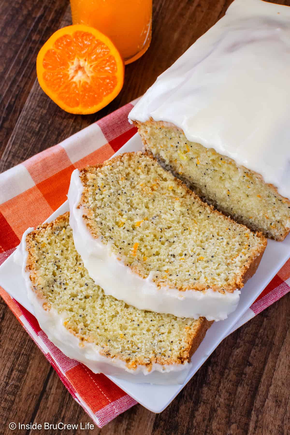 A loaf of orange bread on a plate with two slices lying in front of it.
