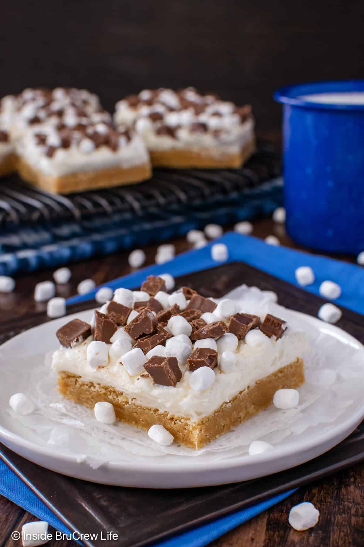 A white plate with a s'mores sugar cookie bar with frosting on it.