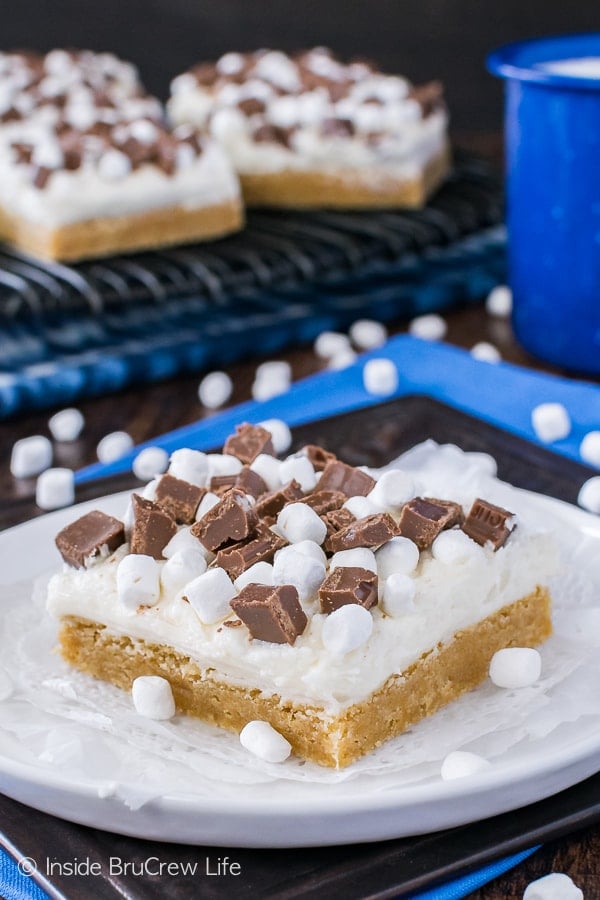 S'mores Sugar Cookie Bars - marshmallow frosting and chocolate chunks add a fun flair to these easy graham cracker cookie bars. Great recipe for summer picnics!