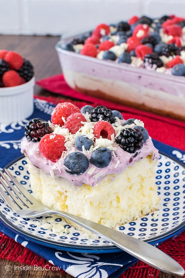 A blue and white plate with a piece of white chocolate pudding cake topped with a berry topping and fresh berries