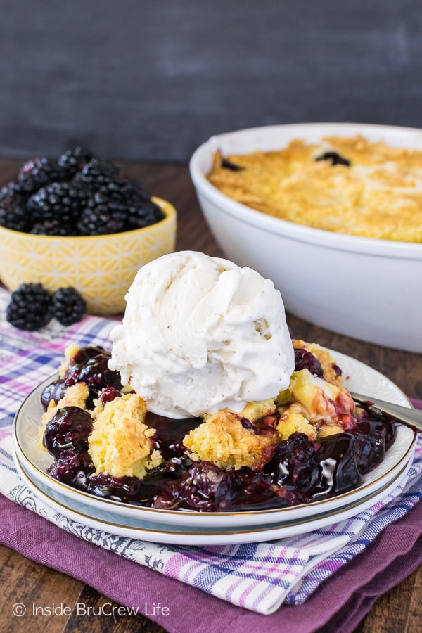 Blackberry Dump Cake - this easy three ingredient cake is delicious when served with a big scoop of ice cream. Great summer dessert recipe to serve a crowd! A white plate with a big scoop of dump cake on it topped with a scoop of vanilla ice cream.