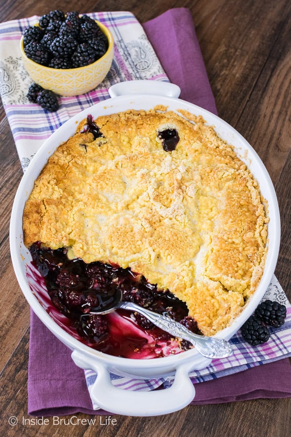 Overhead picture of a white dish with blackberry cobbler in it and a few scoops missing