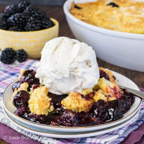 A white plate with scoop of blackberry dump cake topped with vanilla ice cream on it