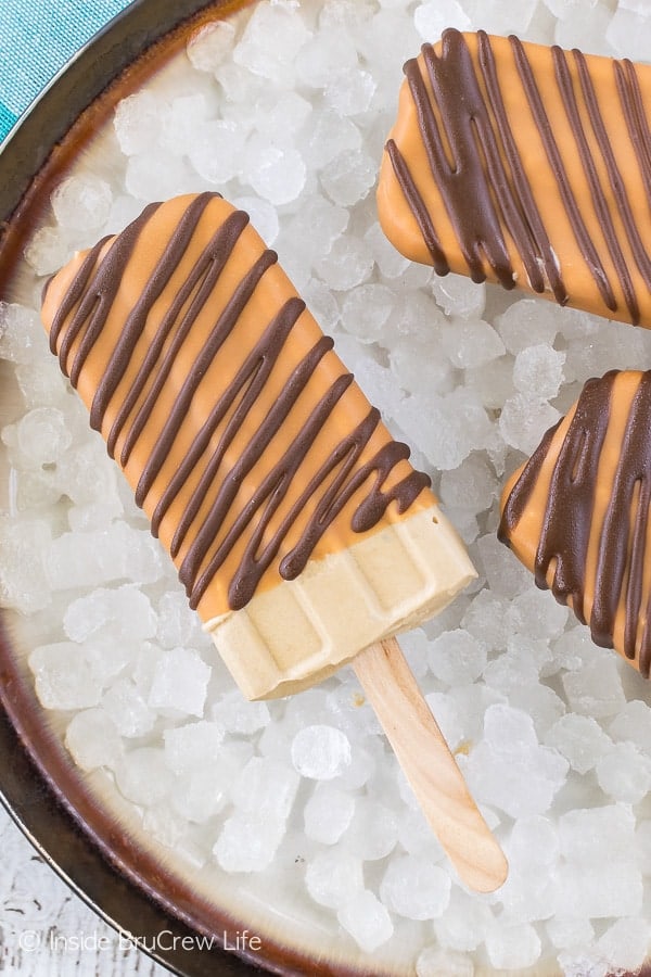 Caramel Frappuccino Pudding Pops - these creamy coffee popsicles are dipped in caramel and drizzled in chocolate. Fun dessert recipe for those hot summer days!