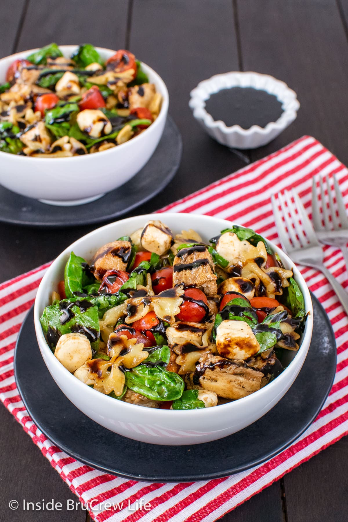 Two white bowls filled with spinach salad and chicken.