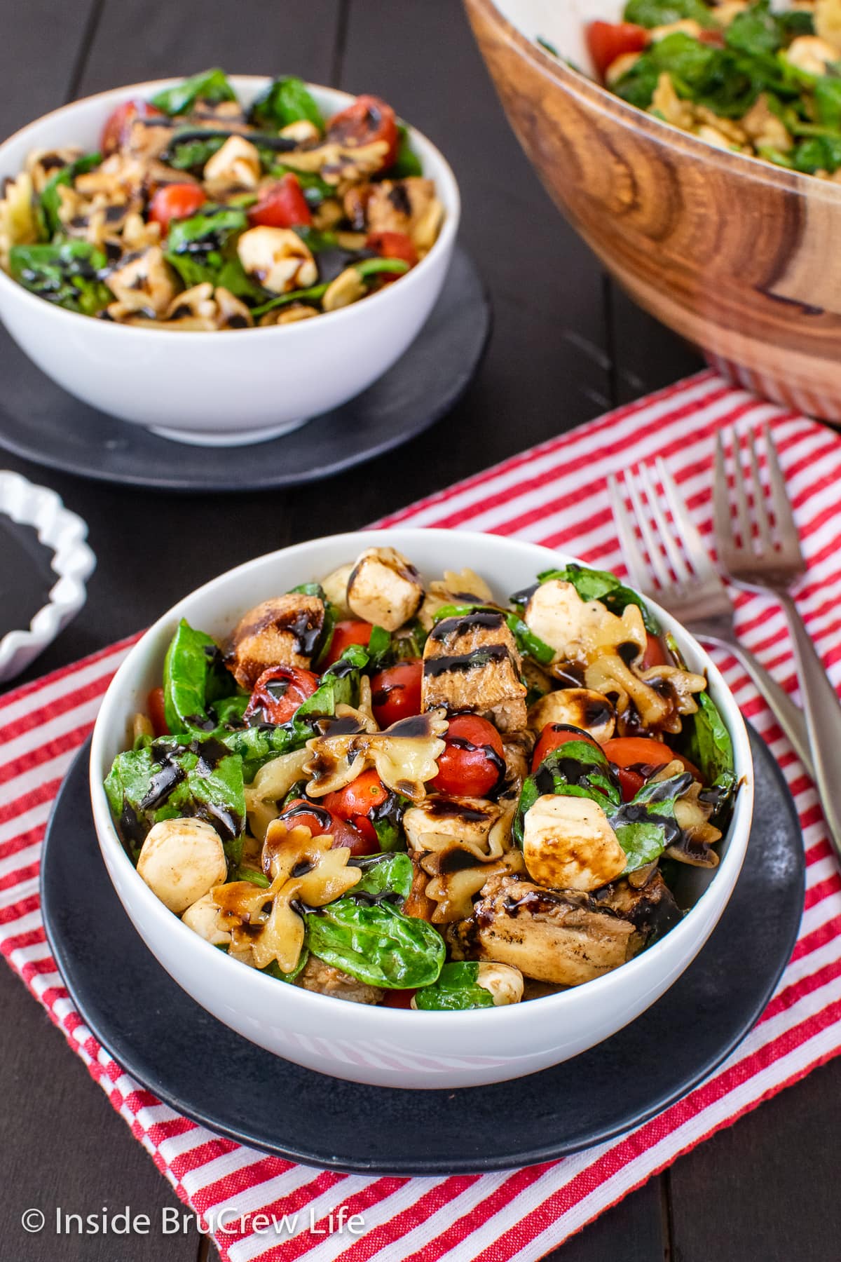 Two white bowls filled with spinach salad and chicken.