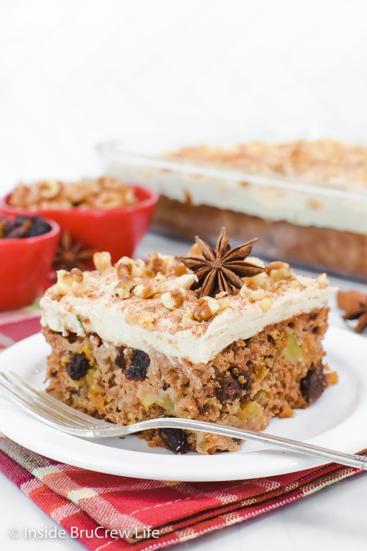 A slice of frosted apple cake on a plate.