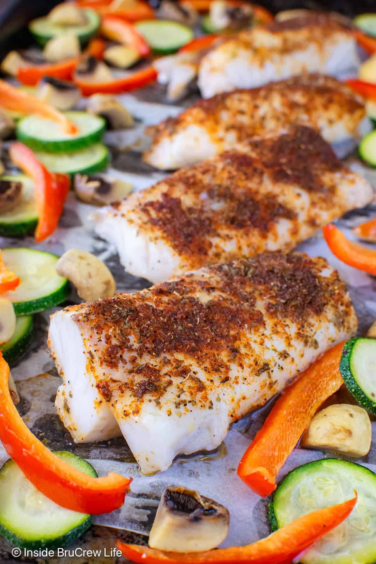 A close up of chili lime cod cooked on a sheet pan with veggies.