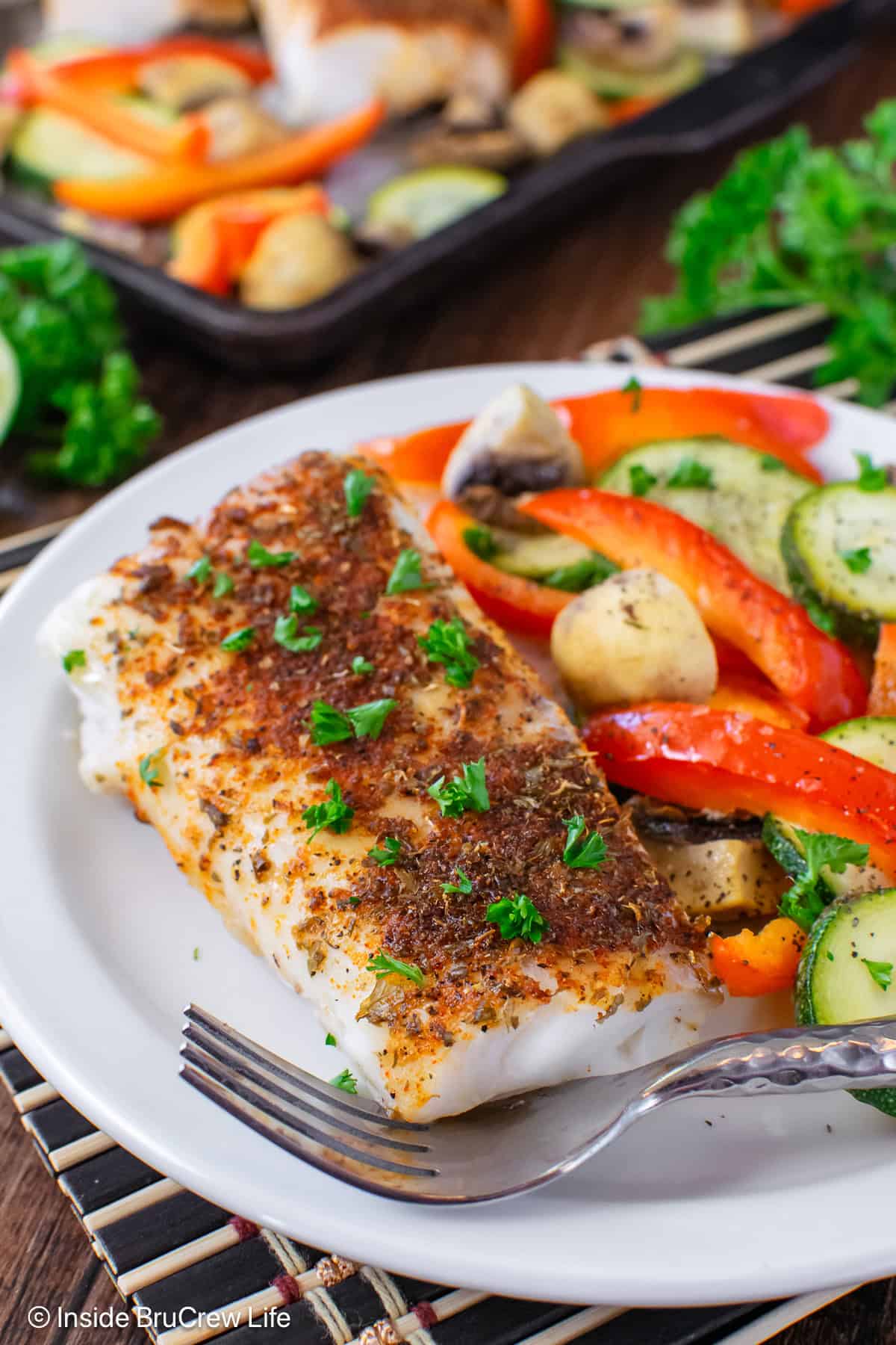 Chili lime cod and roasted veggies on a white plate.