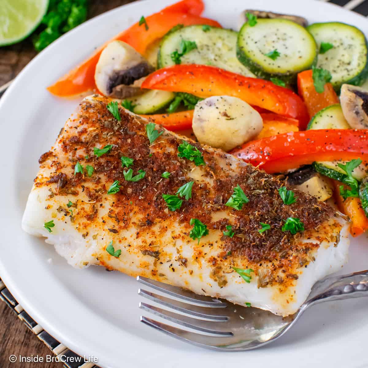 Chili lime cod and roasted veggies on a white plate.