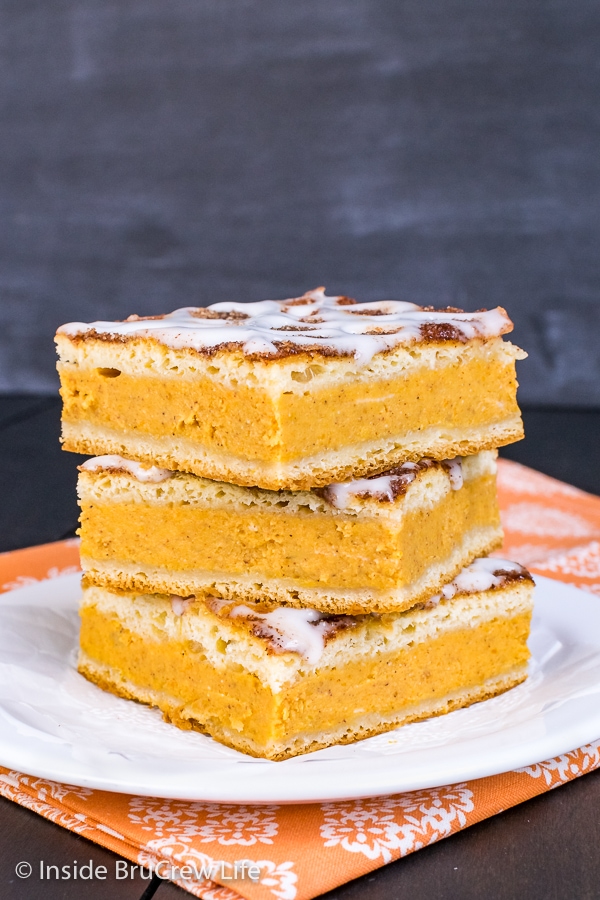 Three squares of churro pumpkin pie cheesecake danish stacked on a white plate