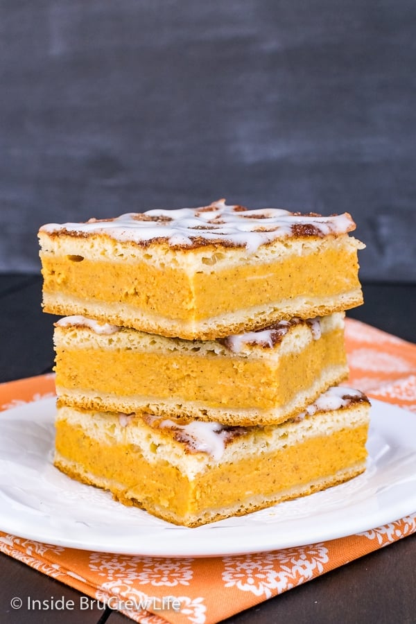 Three squares of churro pumpkin pie cheesecake danish stacked on a white plate