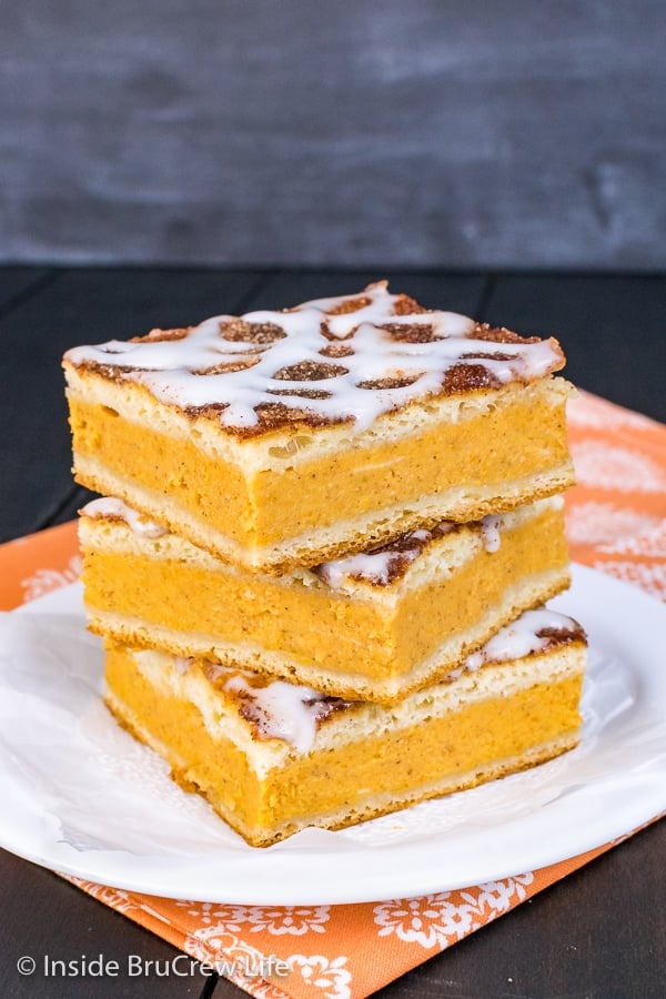 A stack of three churro pumpkin pie cheesecake danishes on a white plate