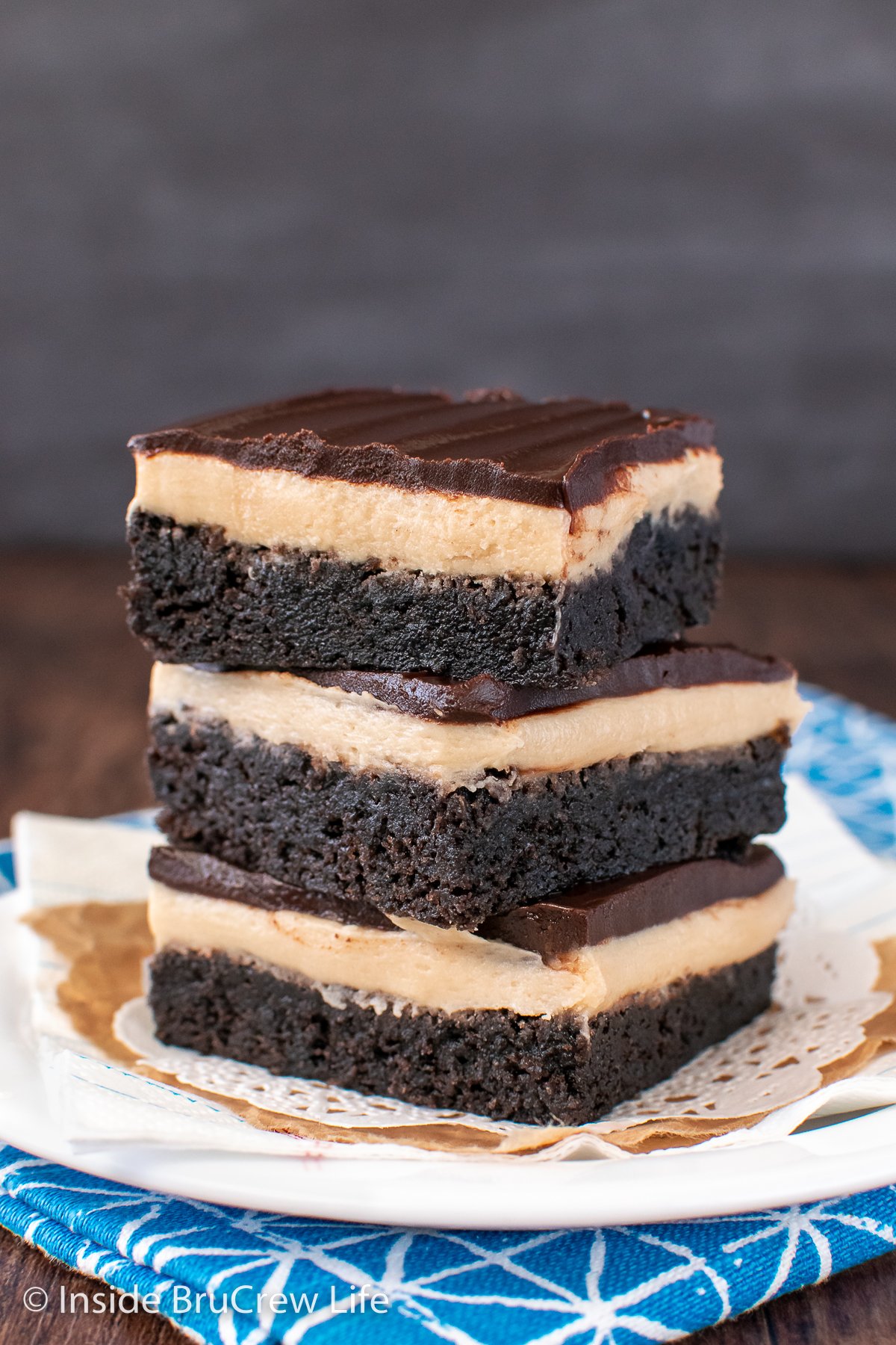 A stack of frosted brownies on a plate.