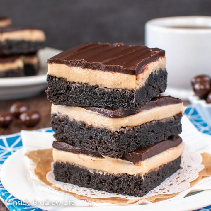 A white plate with three brownies stacked on it.