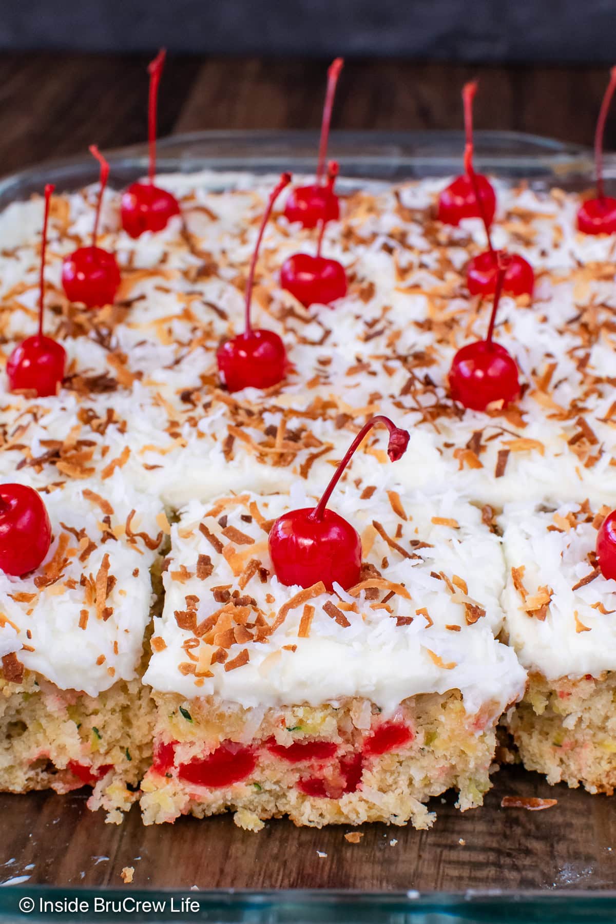 A pan of frosted zucchini cake topped with cherries.