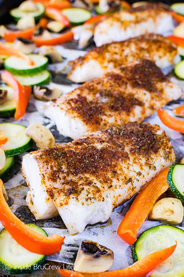 A close up of chili lime cod and roasted veggies on a sheet pan