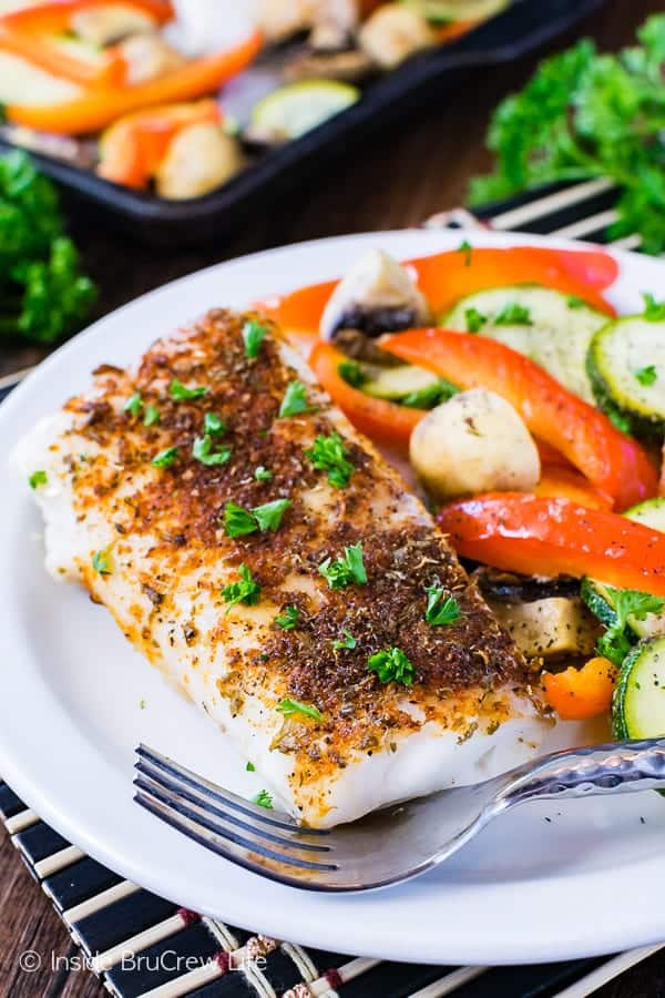 A white plate with chili lime cod and roasted veggies on it