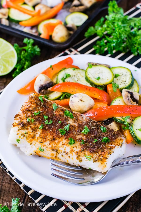 A white plate with chili lime cod and roasted veggies on it