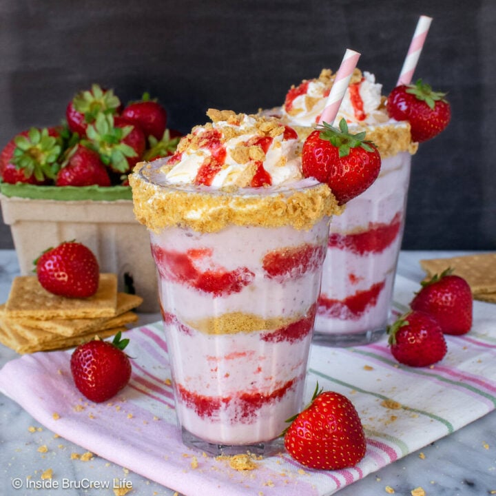 Two glasses filled with strawberry cheesecake milkshake and Cool Whip.