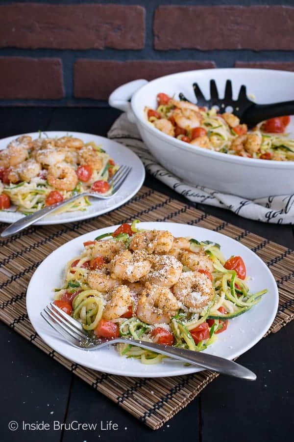 Two white plates with parmesan garlic shrimp zucchini noodles on them