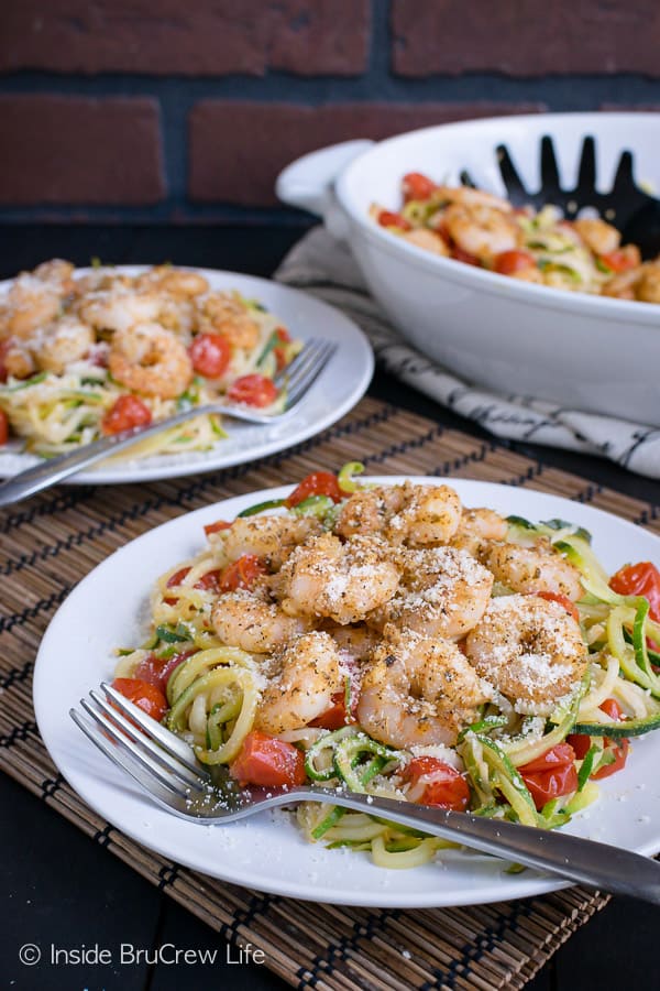 Two white plates with parmesan garlic shrimp zucchini noodles on them