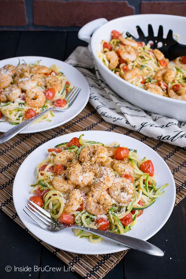 Two white plates with parmesan garlic shrimp and zucchini noodles on them