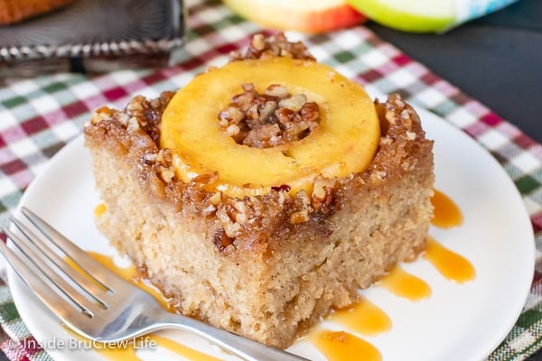 A slice of caramel apple upside down cake on a white plate with caramel drizzles.