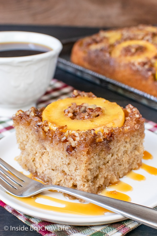 A white plate with caramel drizzles and a slice of apple upside down cake on it.