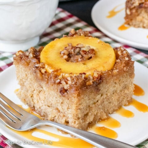 A white plate with caramel drizzles and a square of apple upside down cake on it.