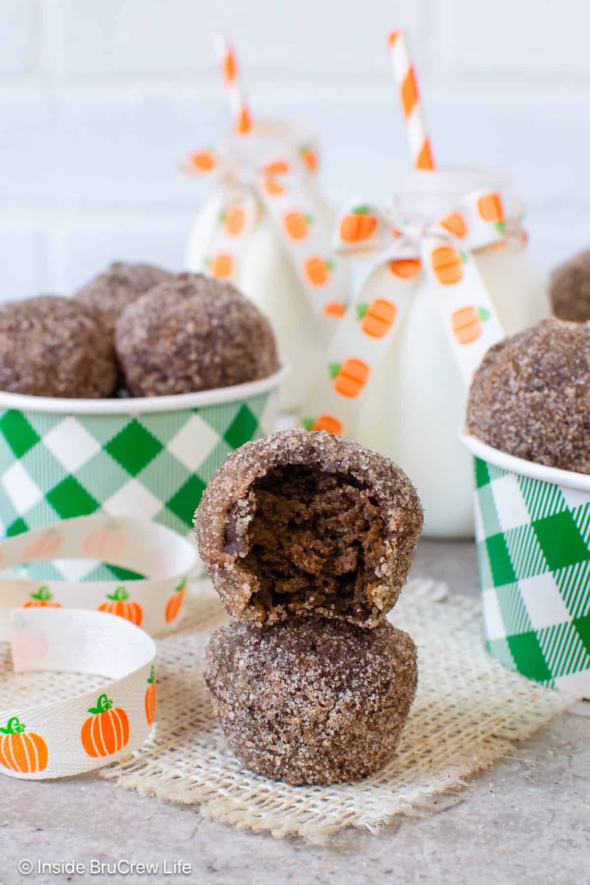 Two sugared chocolate pumpkin donut holes stacked on top of each other.