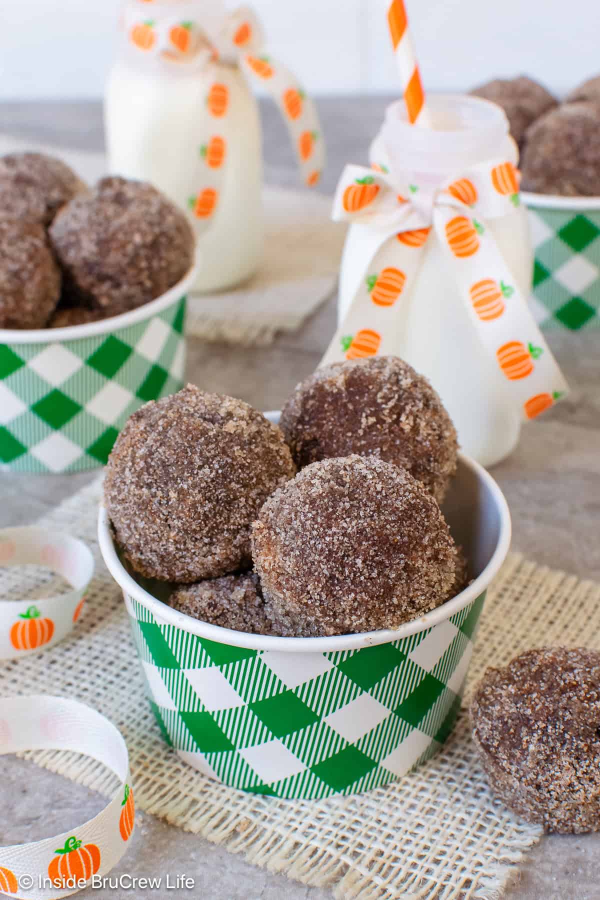 A green and white container filled with sugar coated chocolate donut holes.