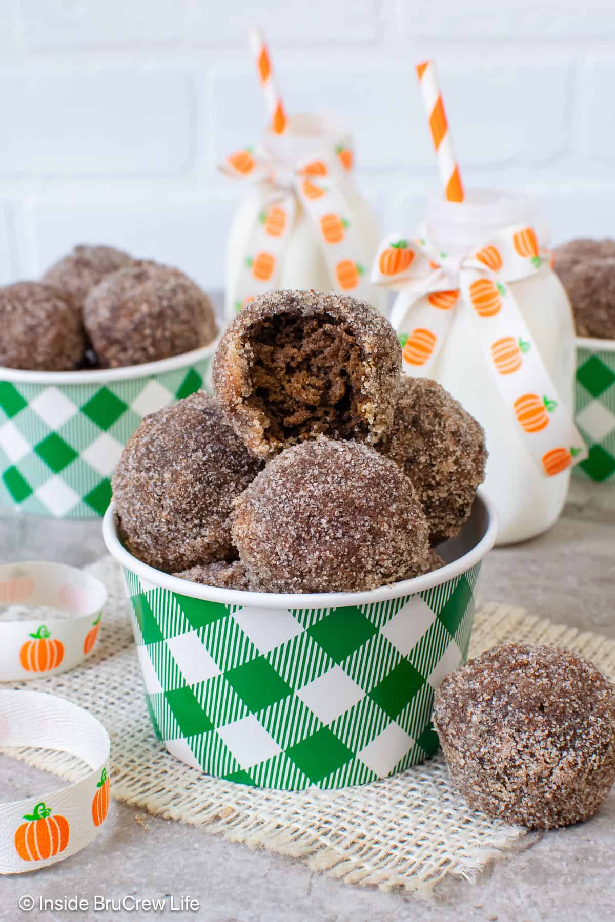 Chocolate pumpkin mini donuts with sugar in a green and white container.
