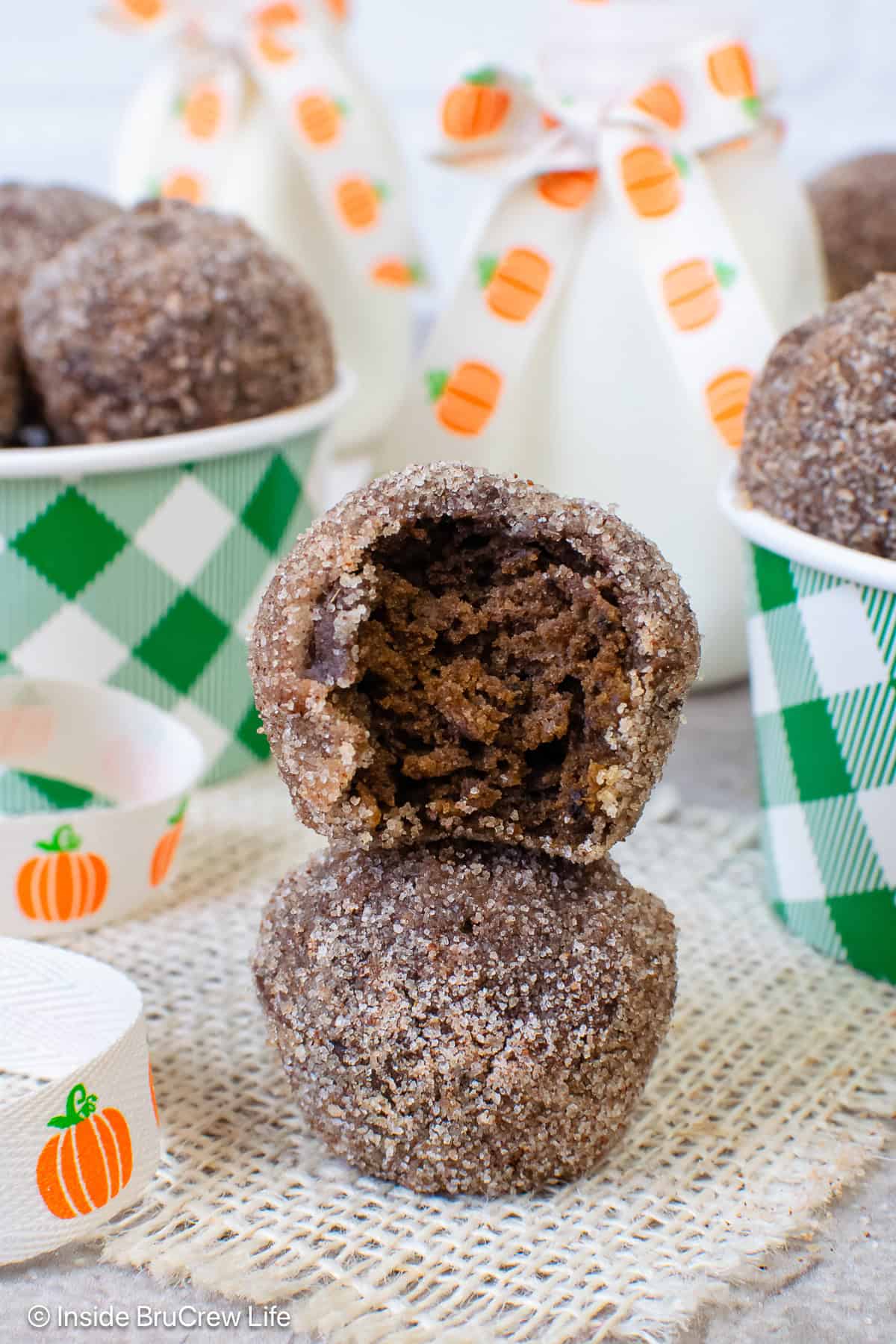 Two sugared chocolate pumpkin mini donuts stacked on top of each other.