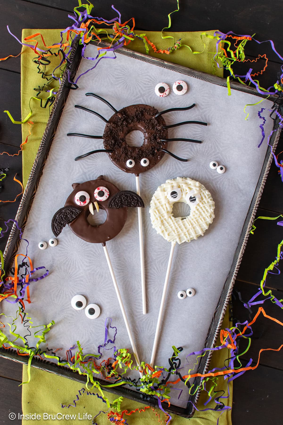 Three chocolate dipped spooky apples on a tray.