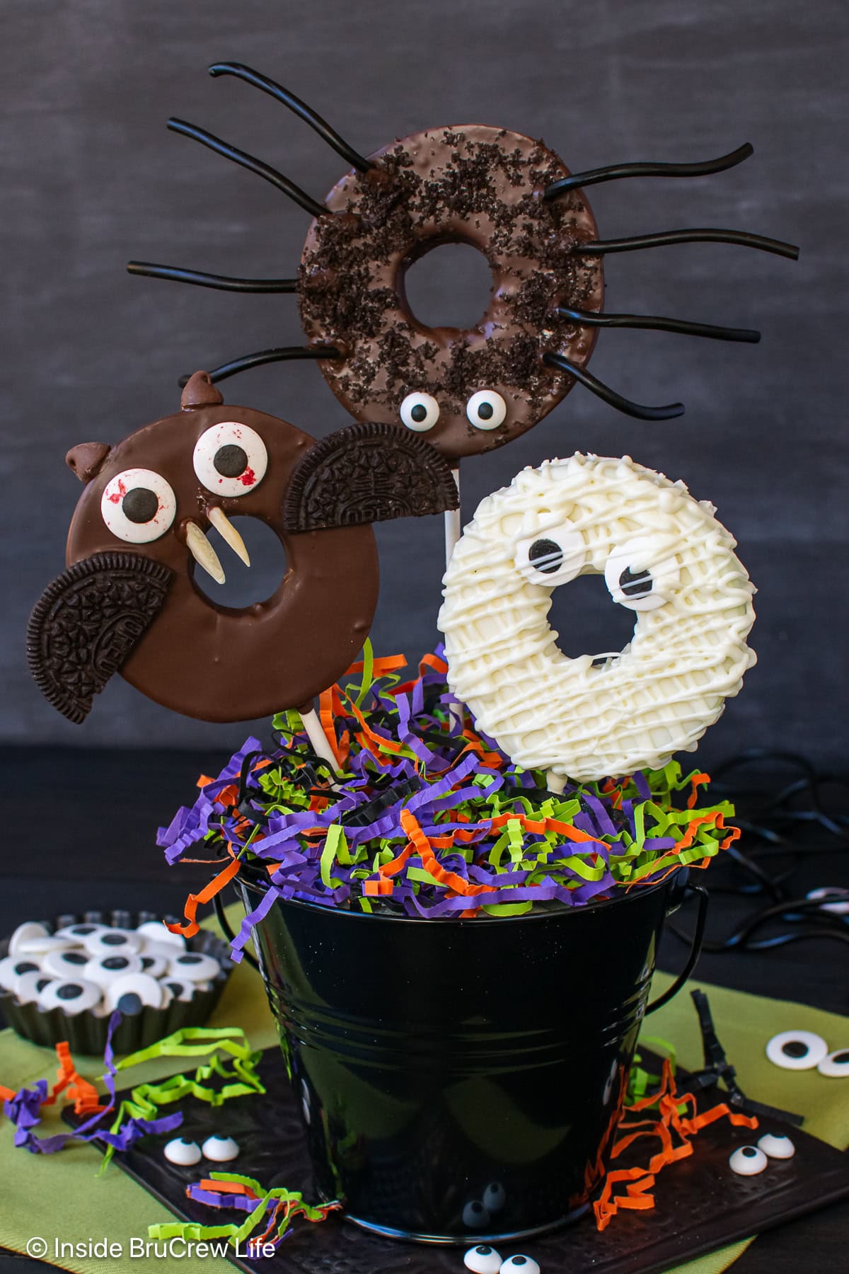 Chocolate monster apple slices on sticks in a black pot.