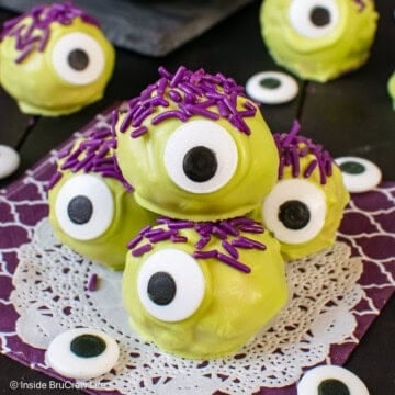 A pile of peanut butter monsters with purple sprinkle hair on a purple napkin.