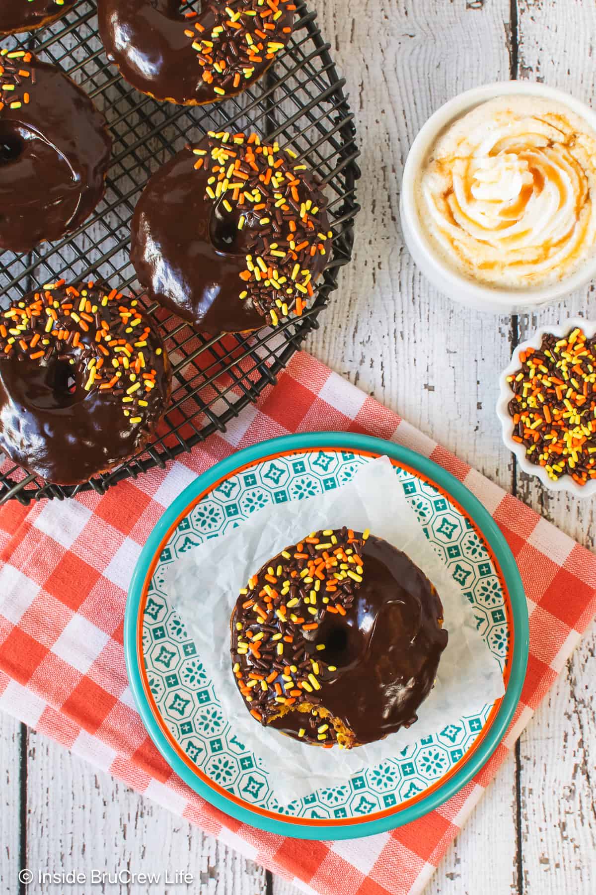 Overhead picture of pumpkin chocolate chip donuts on a plate and cooling rack.