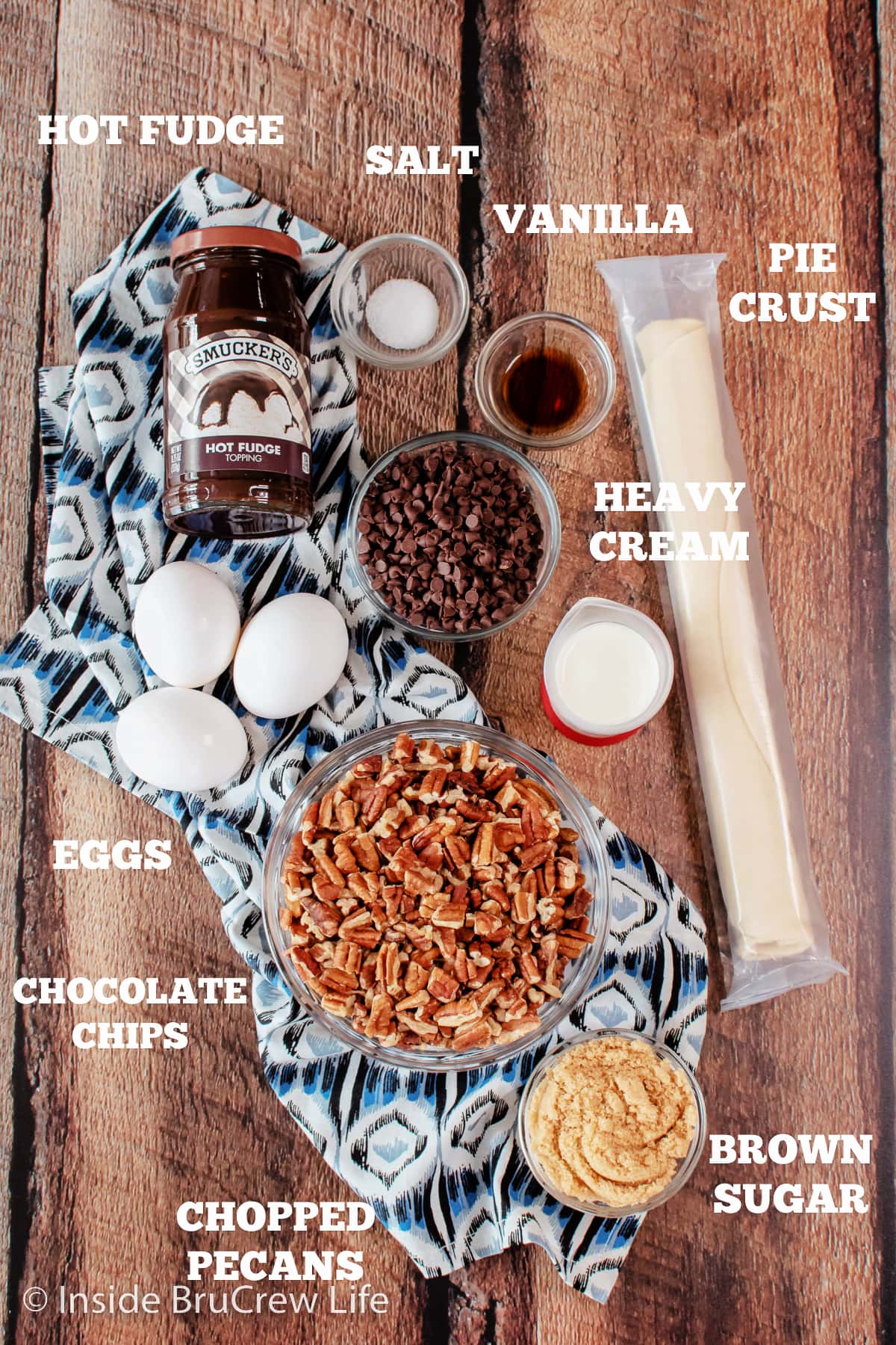 A brown board with bowls of ingredients needed to make a chocolate pie with pecans on it.
