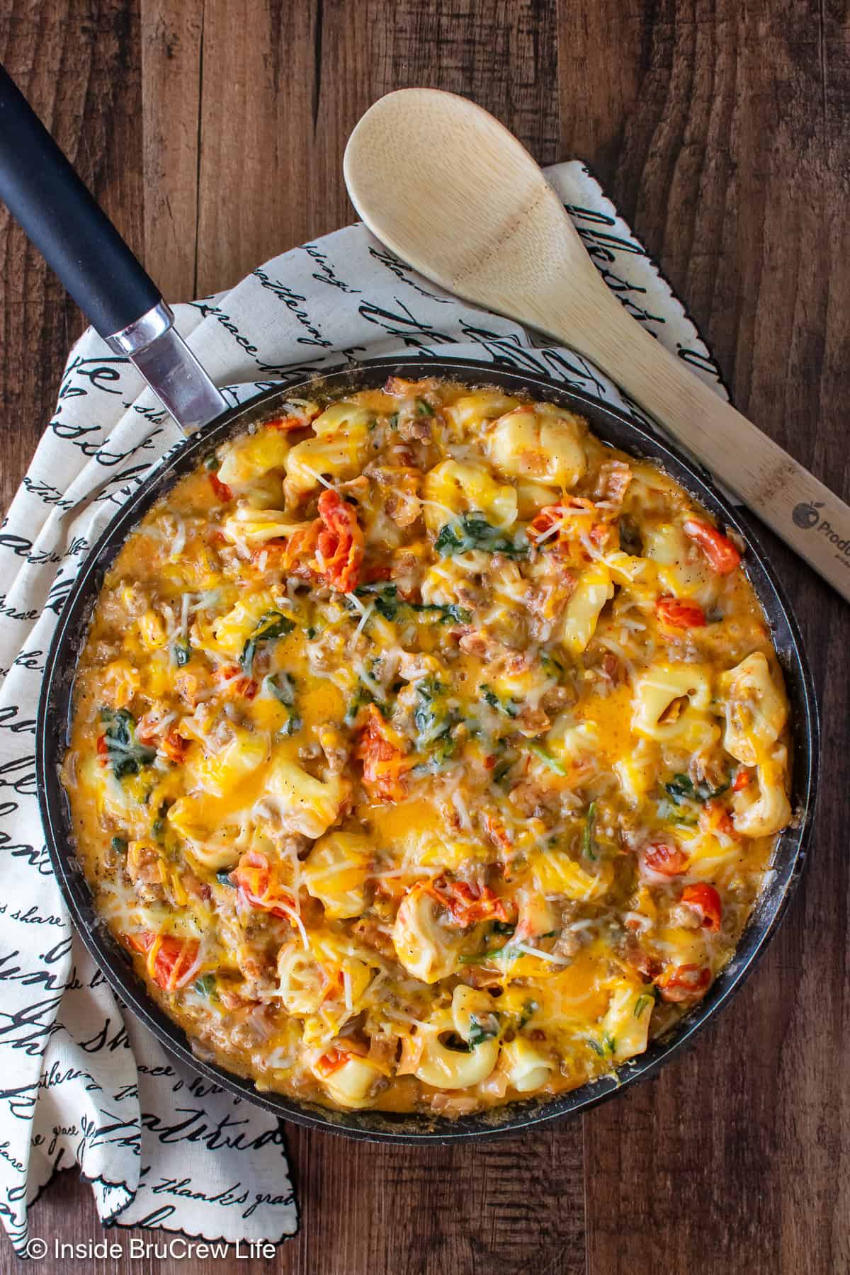 An overhead picture of a black skillet filled with cheesy beef and tortellini.